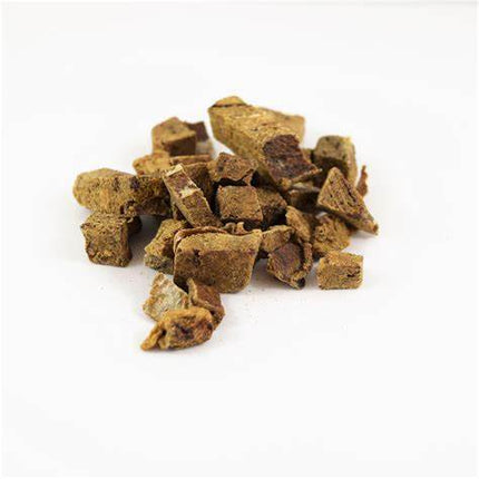 Pile of small freeze-dried pork liver pieces for dogs on a white surface.