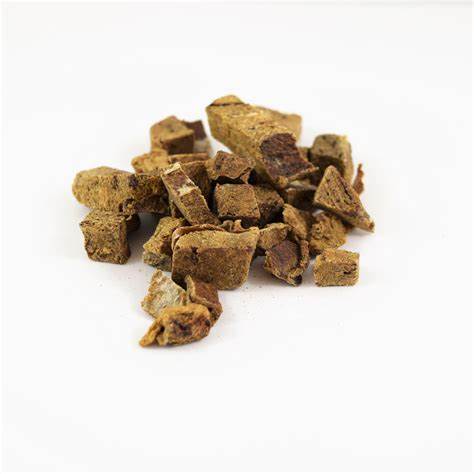 Pile of small freeze-dried pork liver pieces for dogs on a white surface.