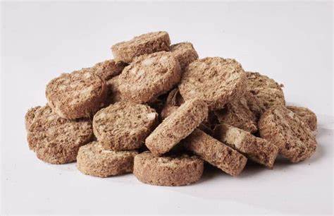 Pile of round, freeze-dried duck gizzard pieces for dogs on a white background.