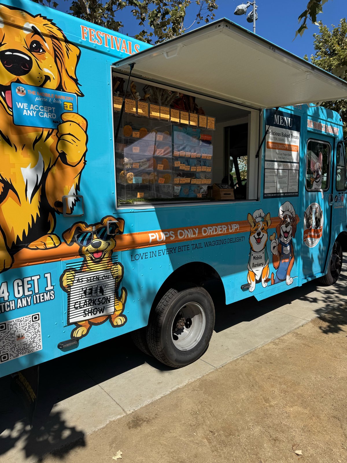The Mobile Barkery truck, bright blue with a golden retriever mural and a service window full of dog treats